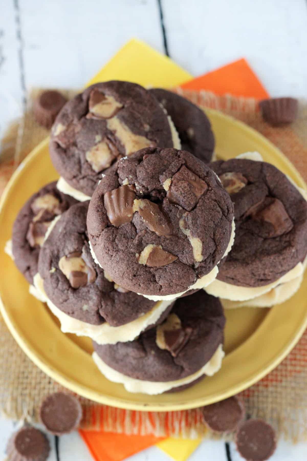 Top view of a pile of Reese's peanut butter cookie sandwiches on a yellow plate.