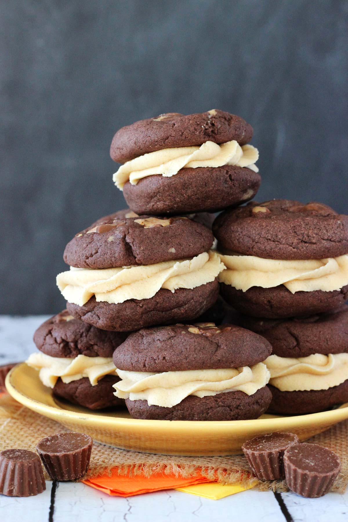 A yellow plate stacked with Reese's peanut butter cookie sandwiches.