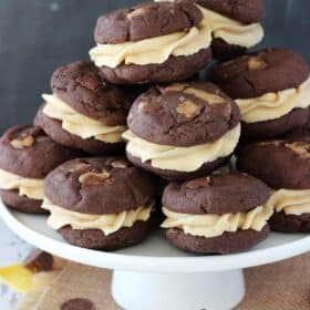 Side view of a white cake stand piled high with Reese's peanut butter cookie sandwiches.