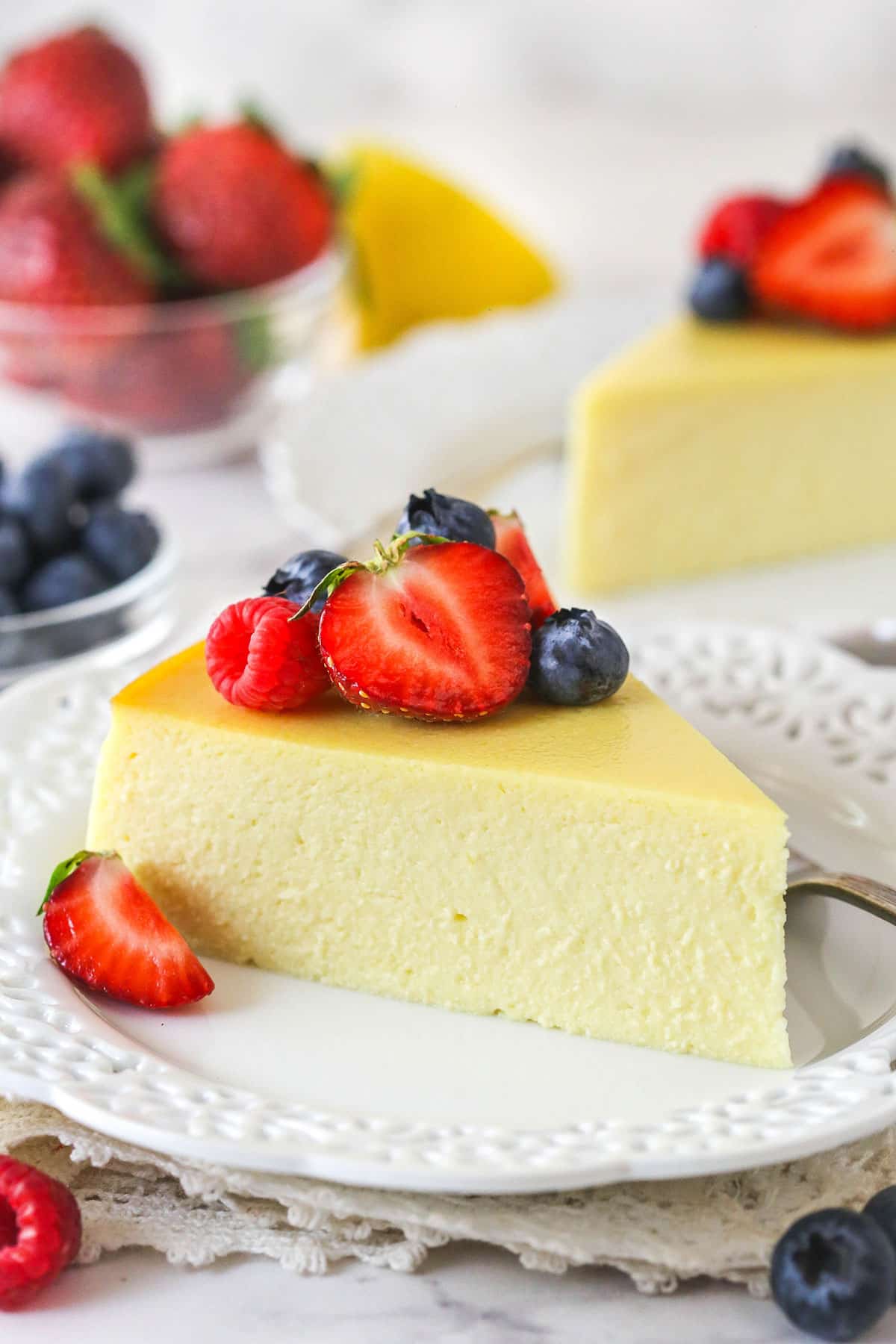 A slice of ricotta cheesecake on a plate topped with fresh berries
