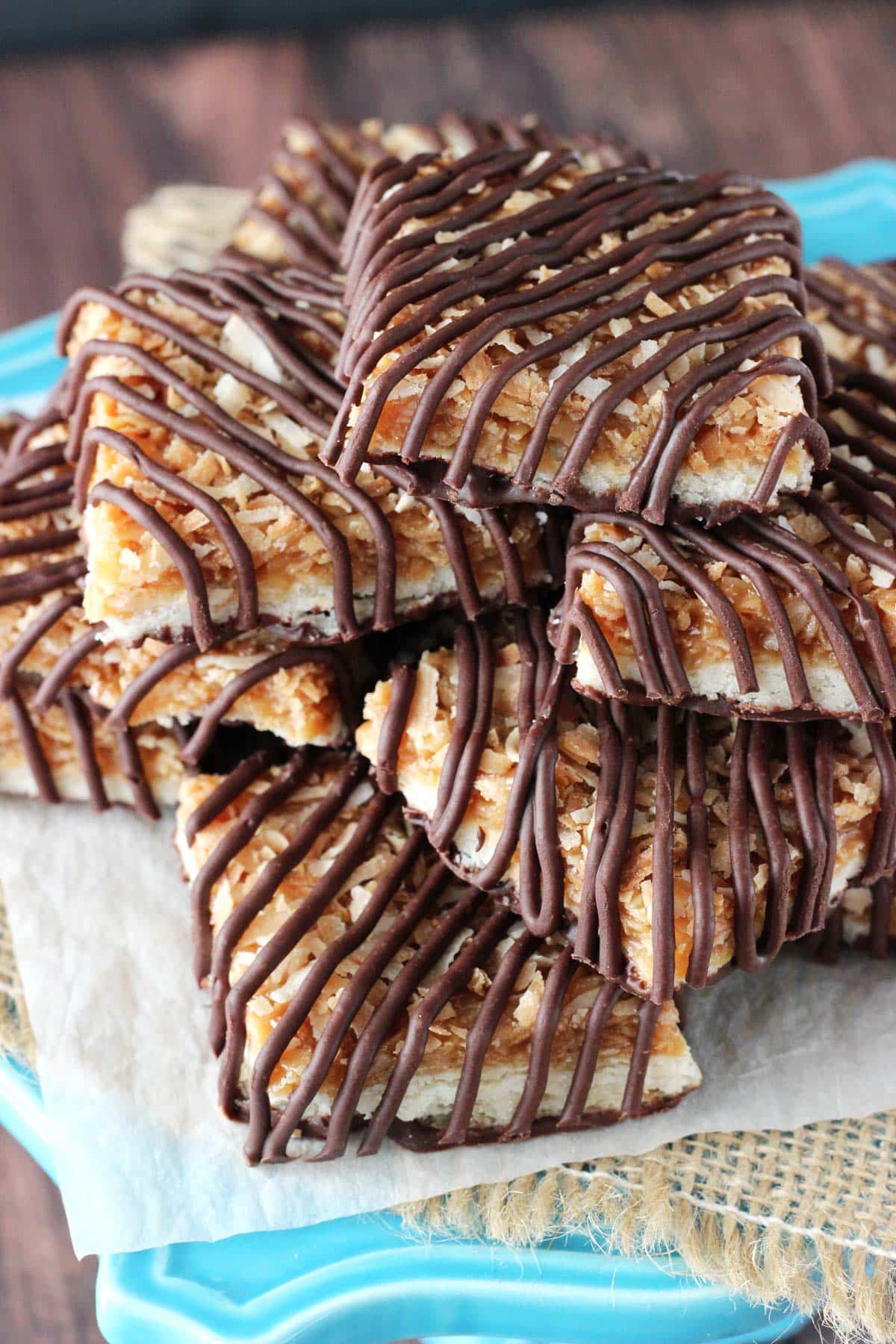 Buttery shortbread cookies are topped with gooey caramel, nutty toasted coconut and rich chocolate in these heavenly Samoa Cookie Bars! Top view of a pile of cut Samoa Cookie Bars.