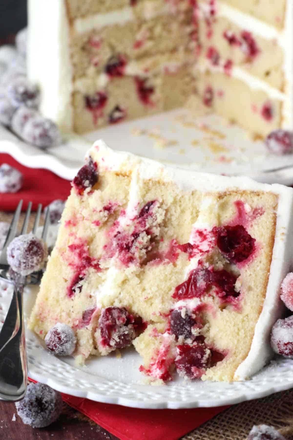 A slice of white chocolate cranberry cake on a small white plate.
