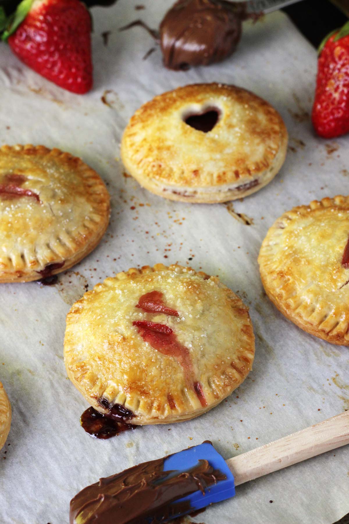 Baked strawberry Nutella hand pies on a piece of parchment.