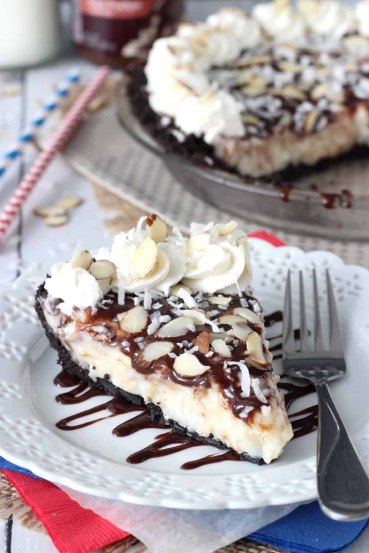 A slice of almond joy pie with the rest of the pie in the background.
