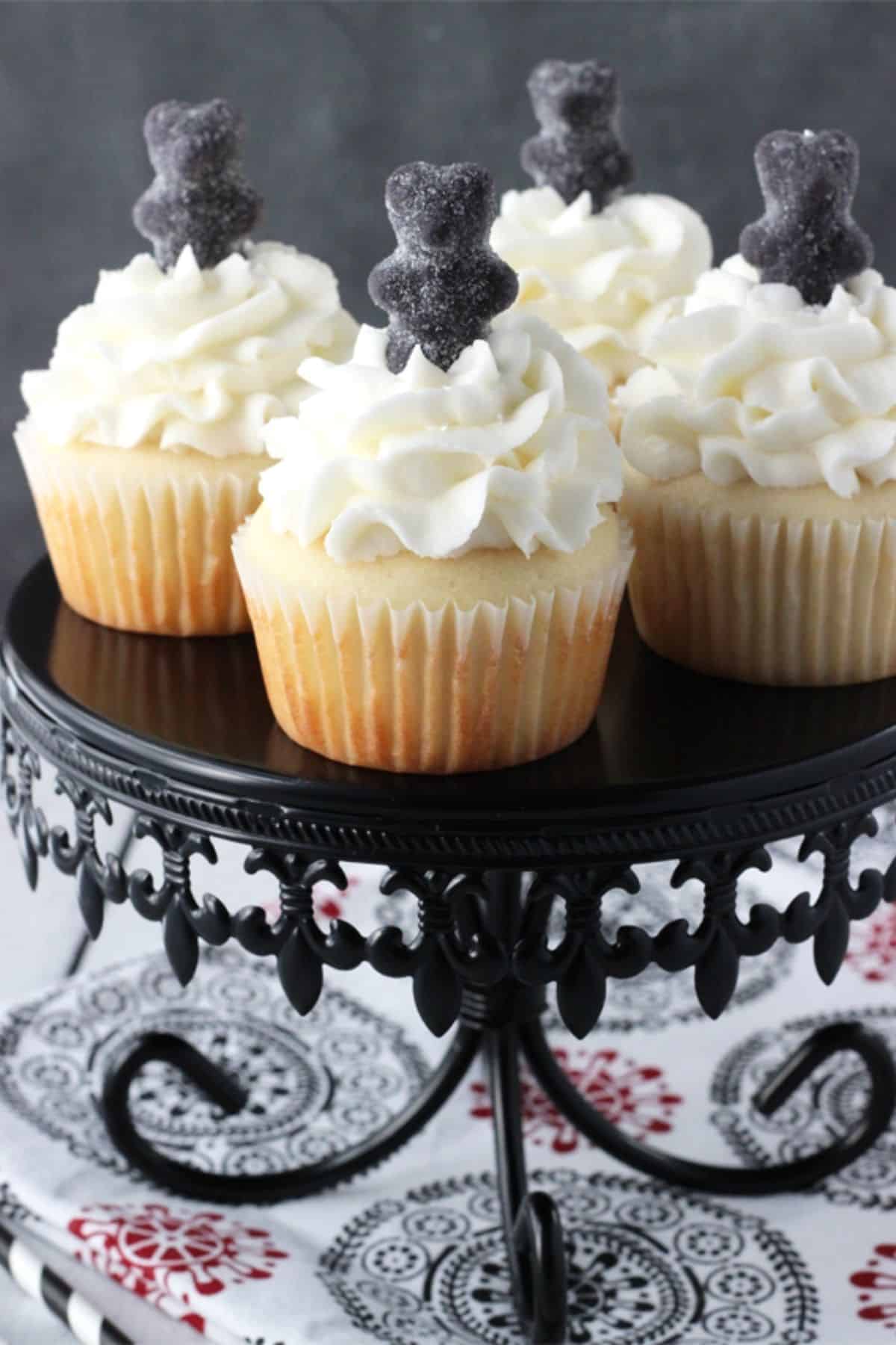 4 anise cupcakes on an ornate black cake stand.