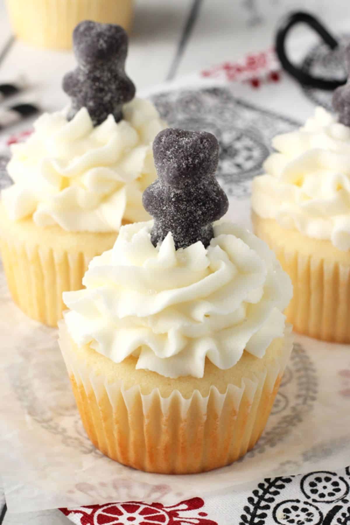 Close up of an anise cupcake with a black gummy bear on top.