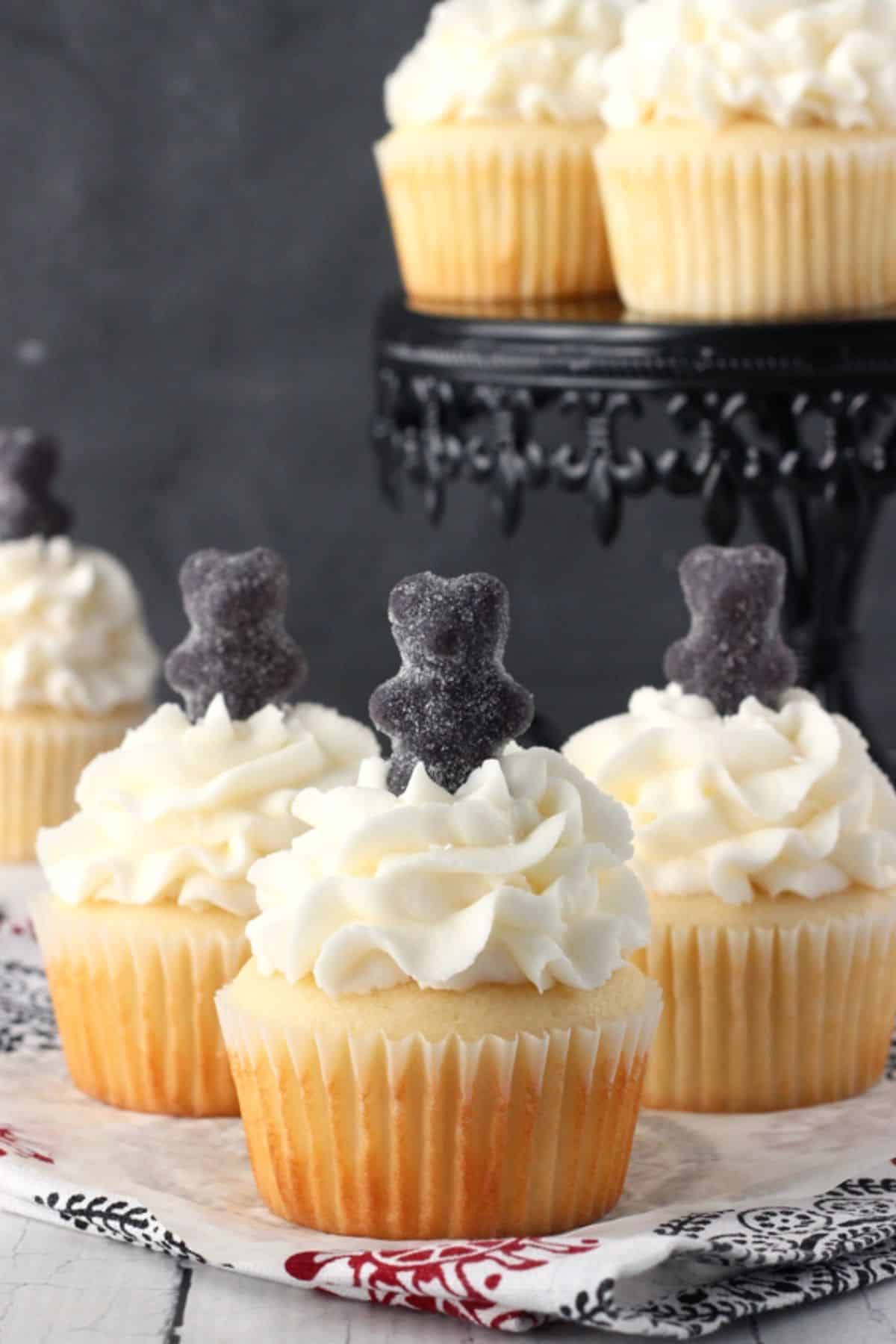 3 anise cupcakes with a black gummy bears on top.