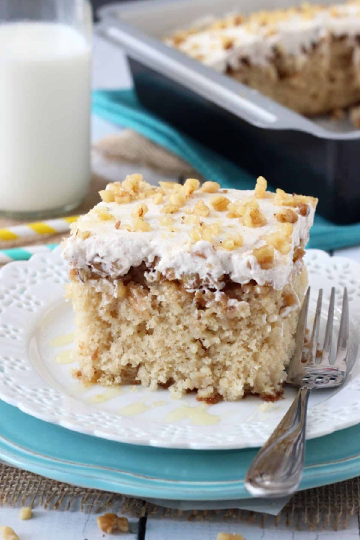 A slice of baklava poke cake on a white plate next to a fork.