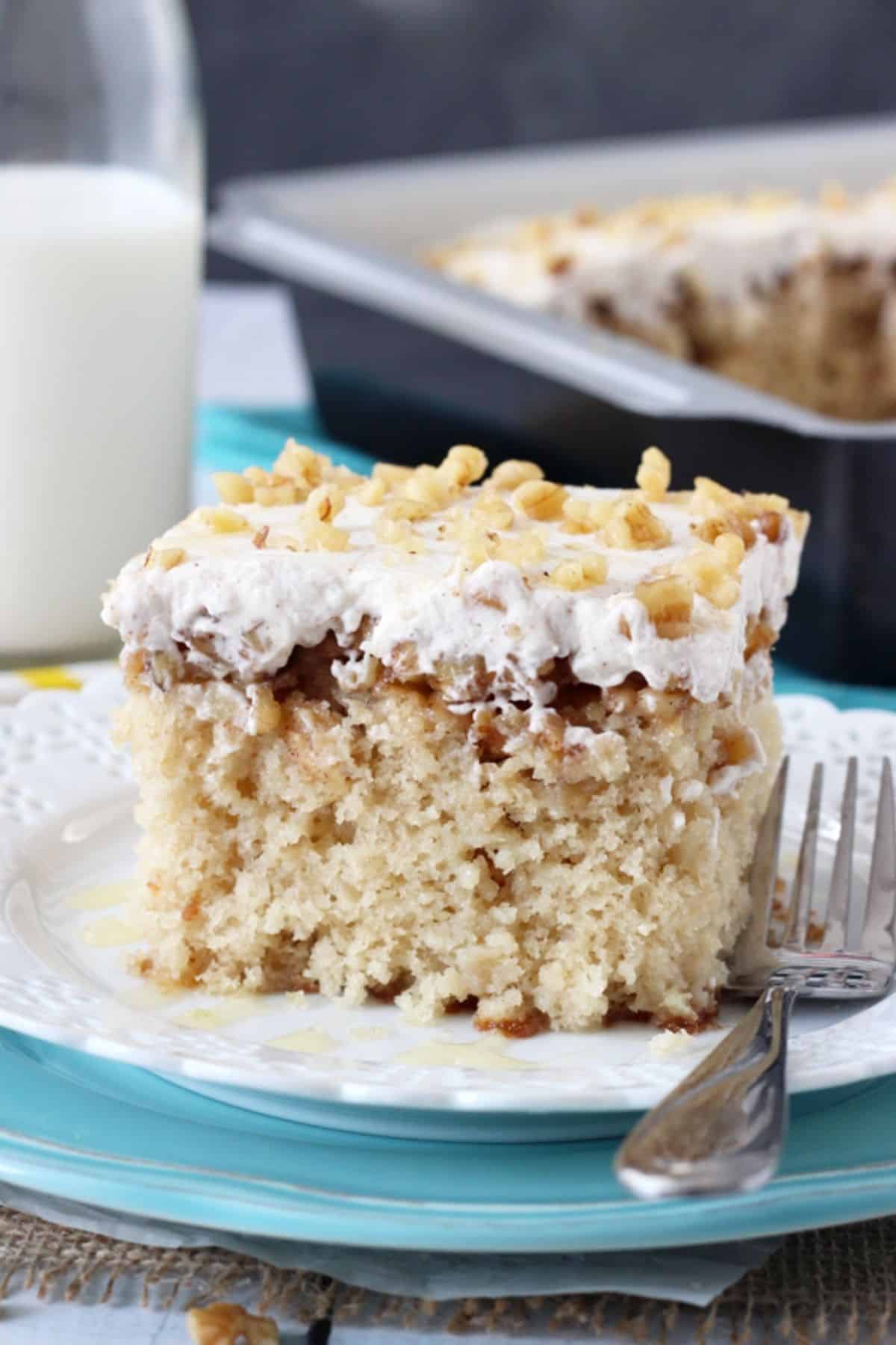 A slice of baklava poke cake on a white plate next to a fork.