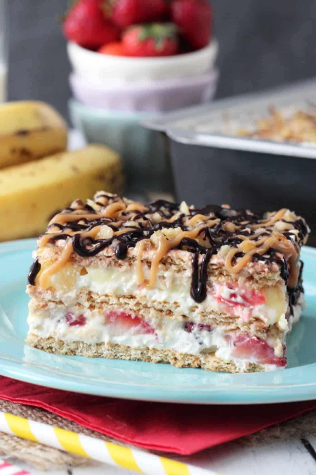Close up of a slice of banana split cake on a blue plate.