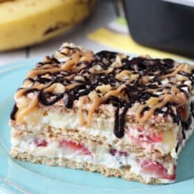 Close up of a slice of banana split cake on a blue plate.