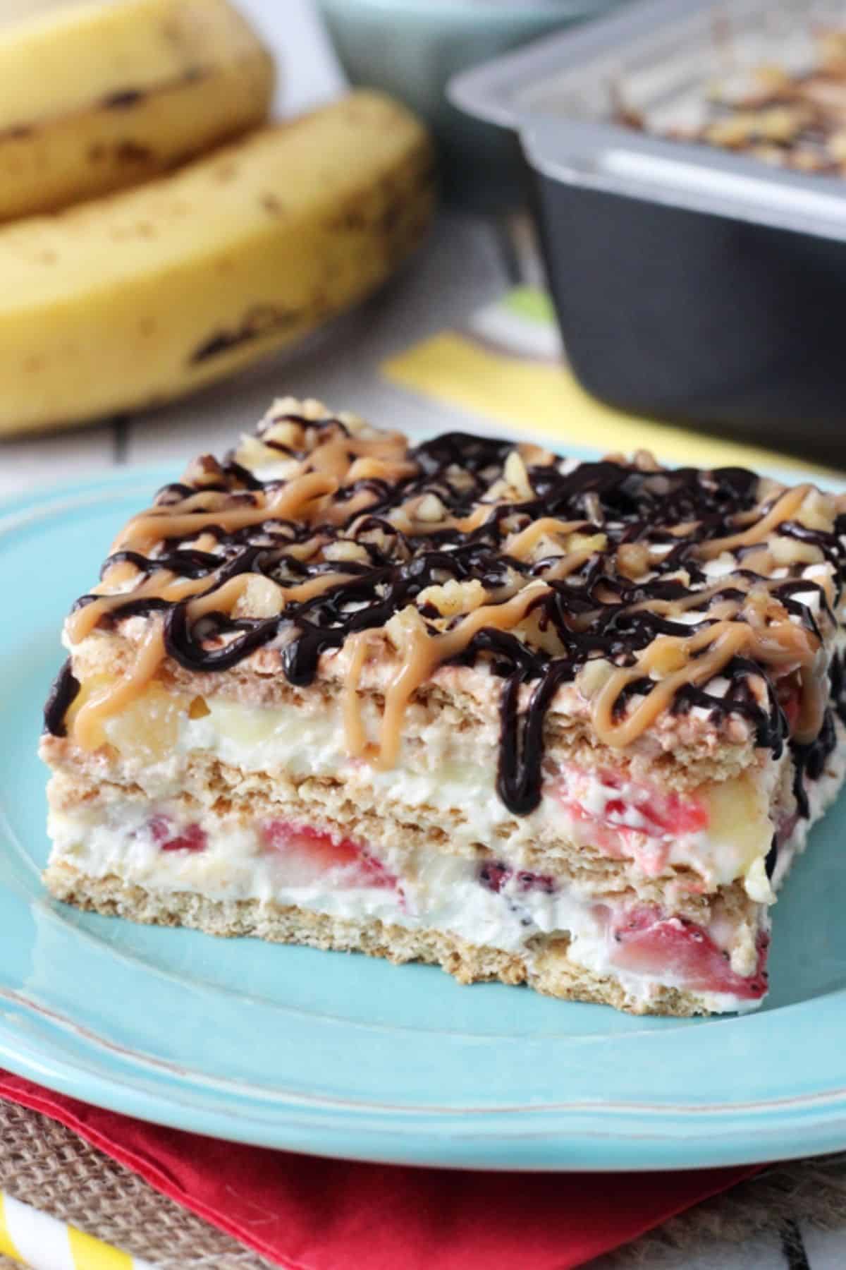 Close up of a slice of banana split cake on a blue plate.