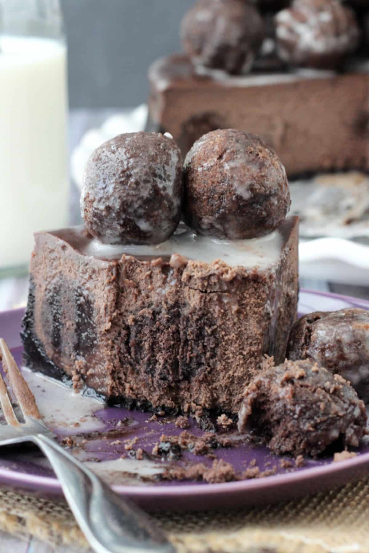 A slice of chocolate donut hole cheesecake with several bites removed.