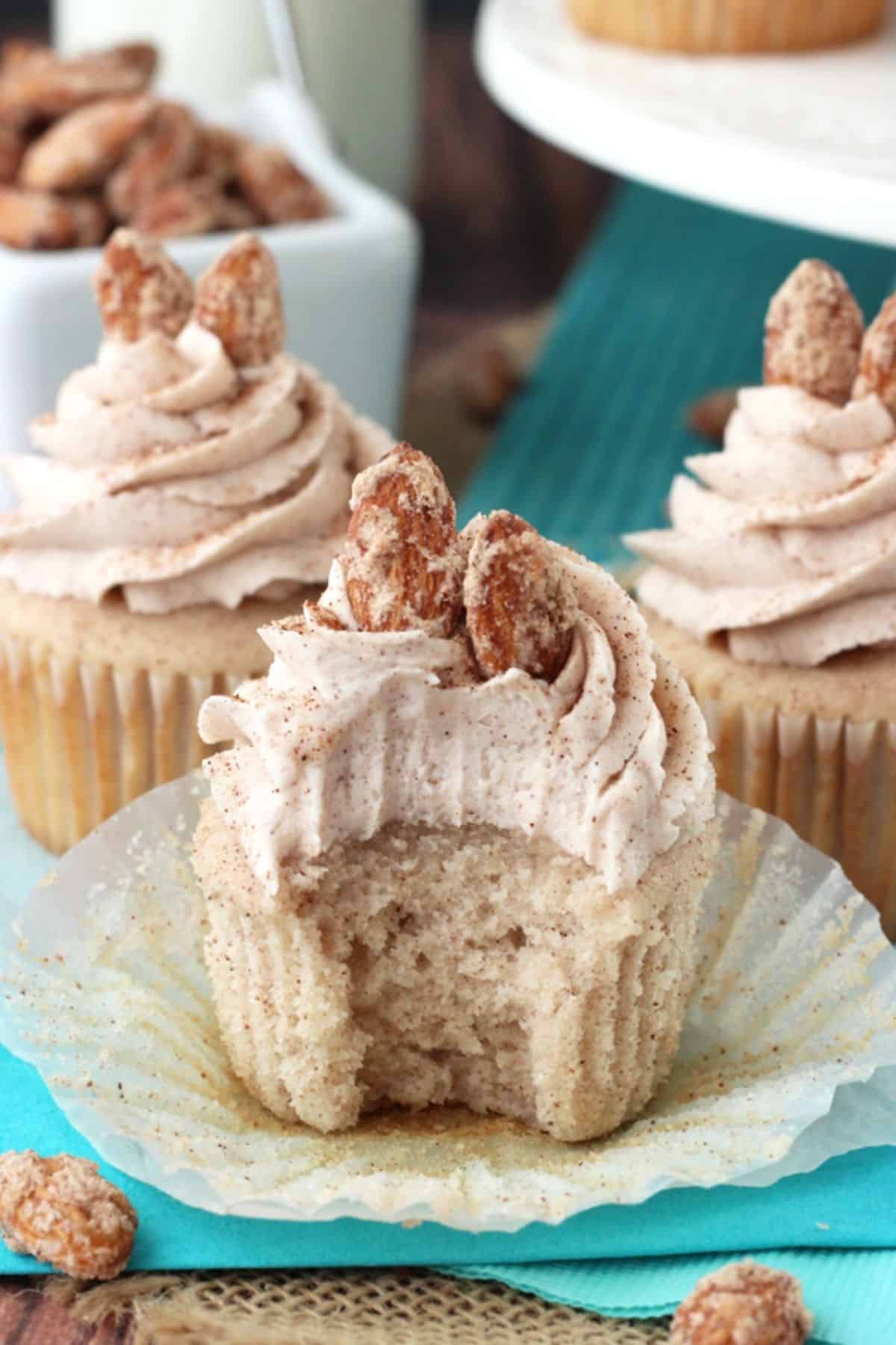 A cinnamon sugar almond cupcake with a bite taken out of it.