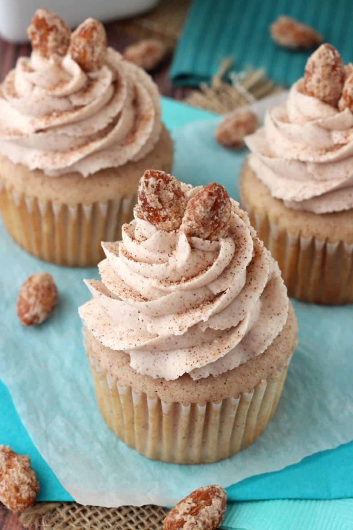 Close up of 3 cinnamon sugar almond cupcakes on a teal napkin.