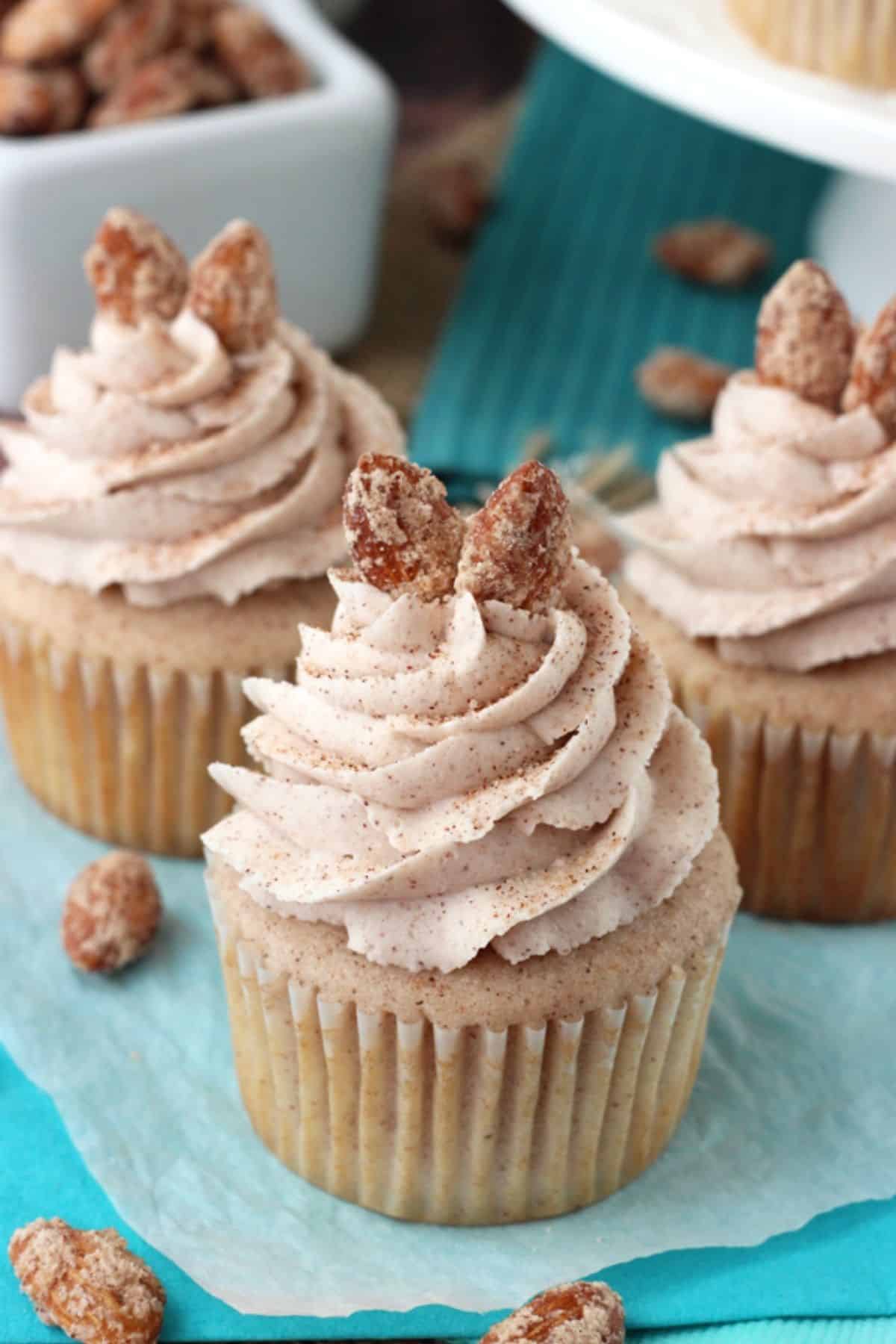 Close up of 3 cinnamon sugar almond cupcakes on a teal napkin.