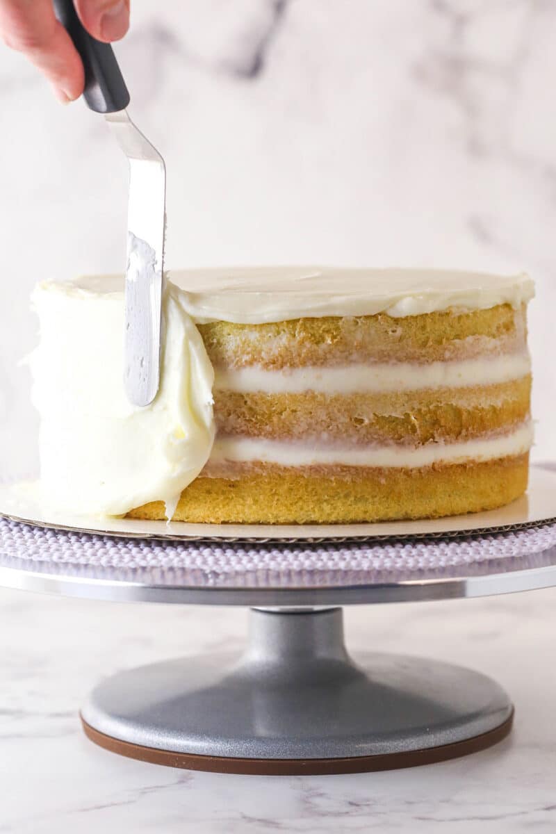 layered cake on turntable with buttercream being spread on the side