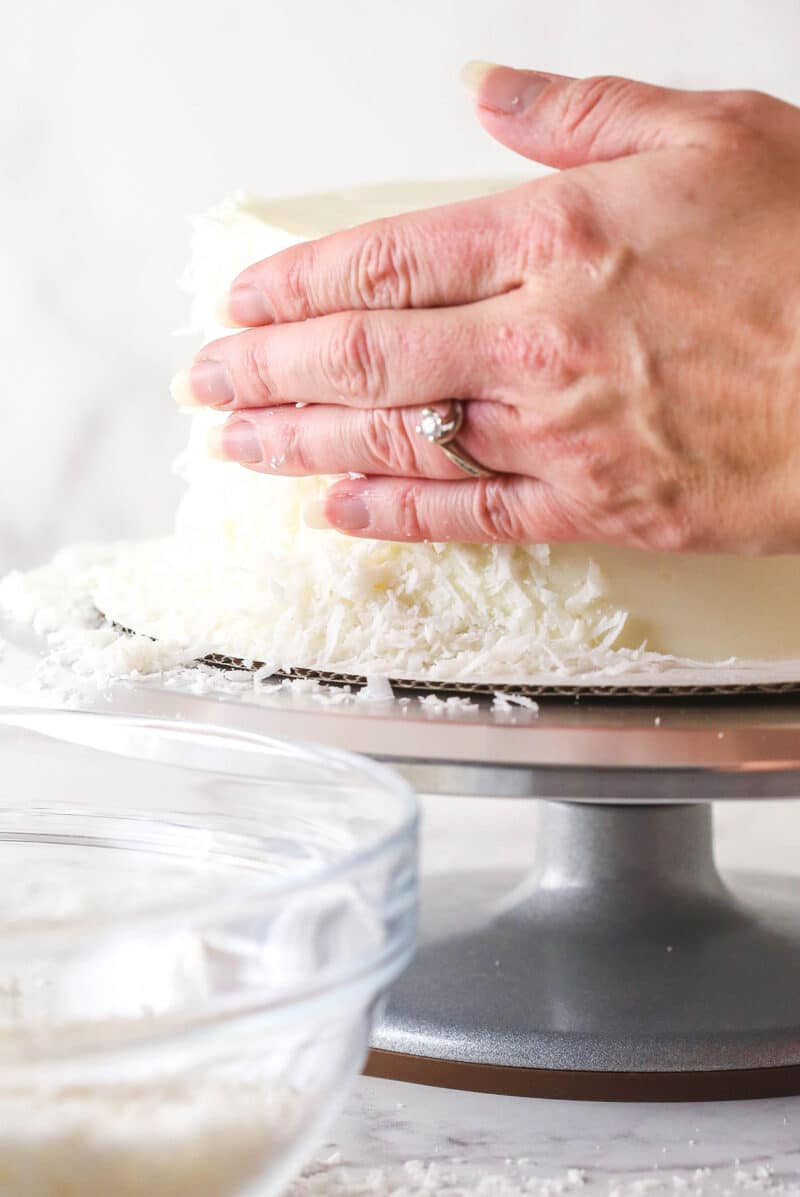 pressing flaked coconut onto the side of the cake on a turntable