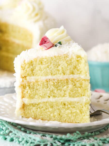 slice of coconut cake on white plate and teal lined napkin