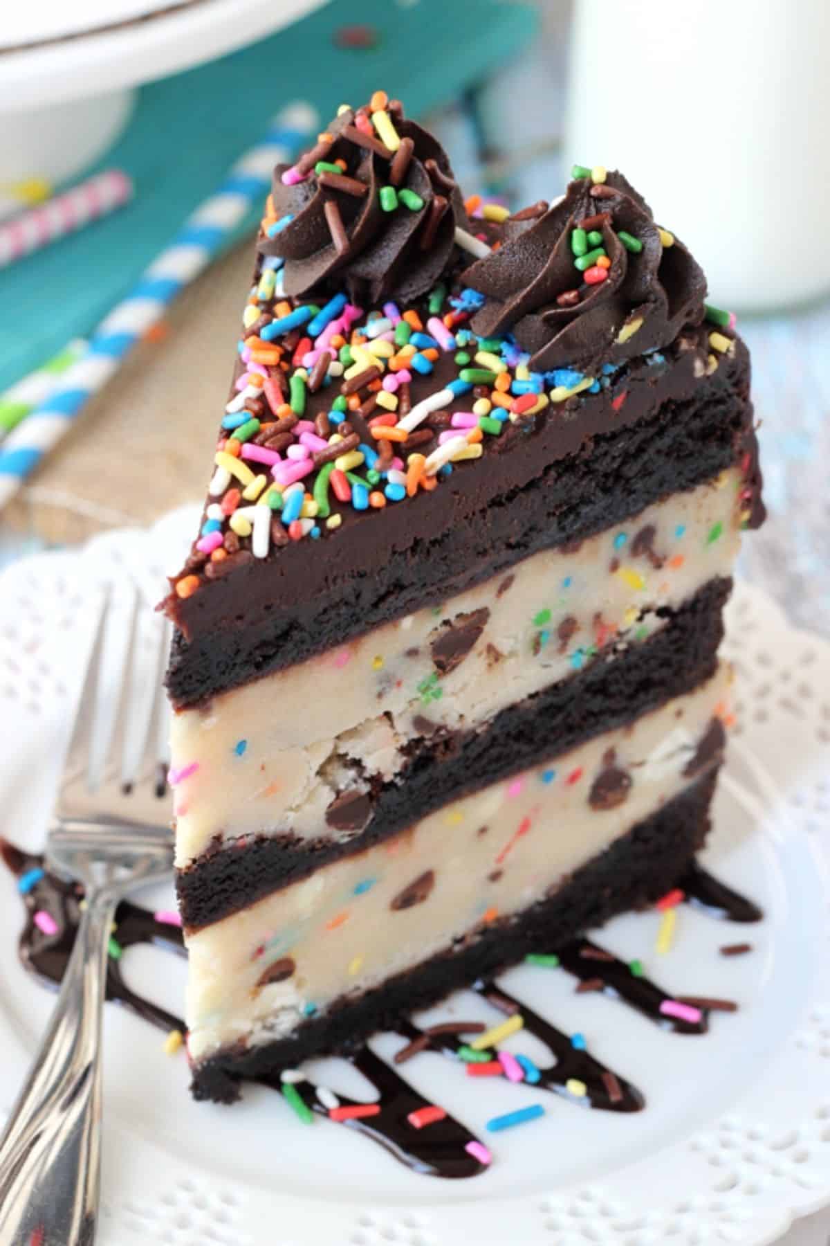 A tall slice of cookie dough brownie layer cake on a small white plate.