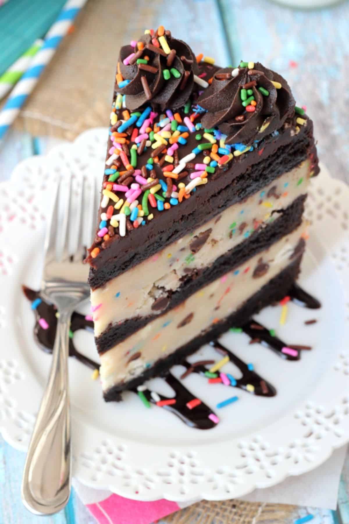 Overhead view of a tall slice of cookie dough brownie layer cake on a small white plate.