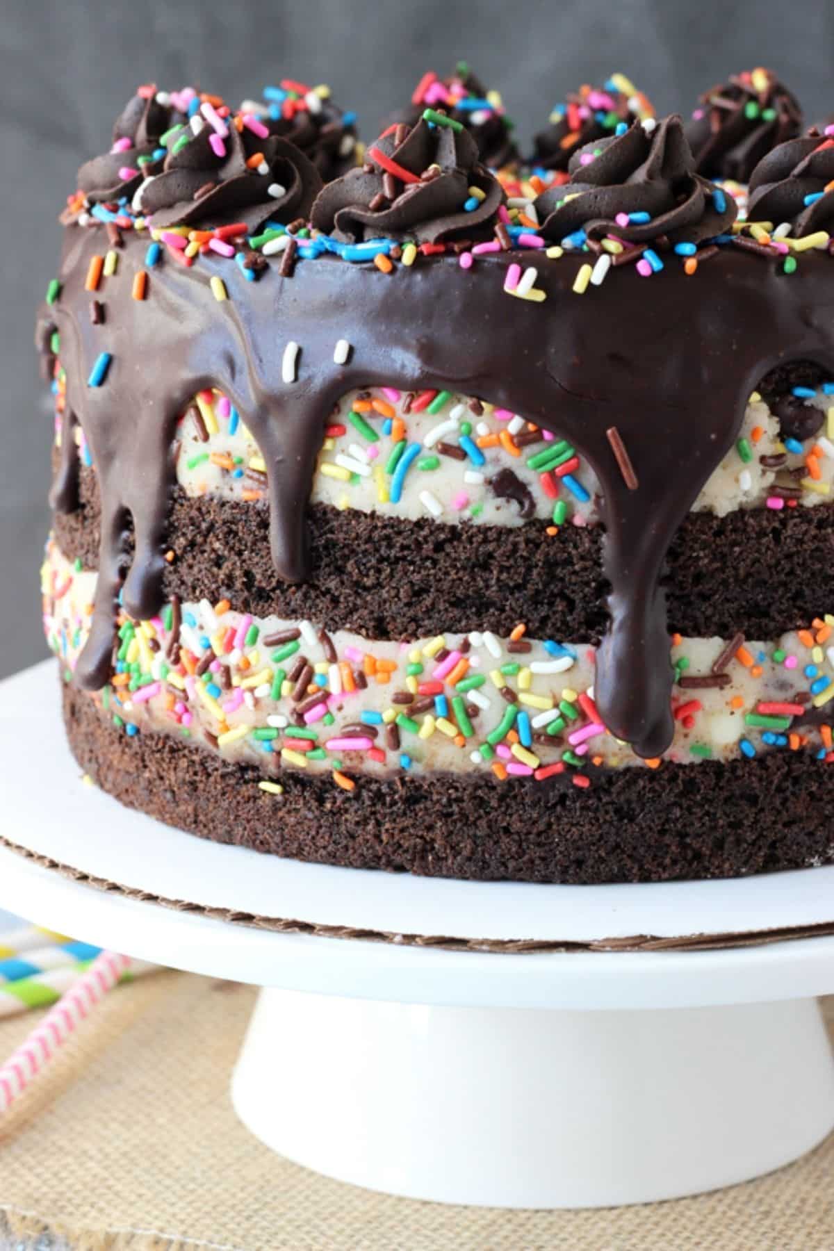 A cookie dough brownie layer cake on a white cake stand.