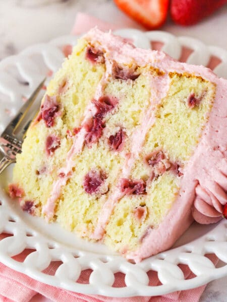 A slice of fresh strawberry cake on a white plate