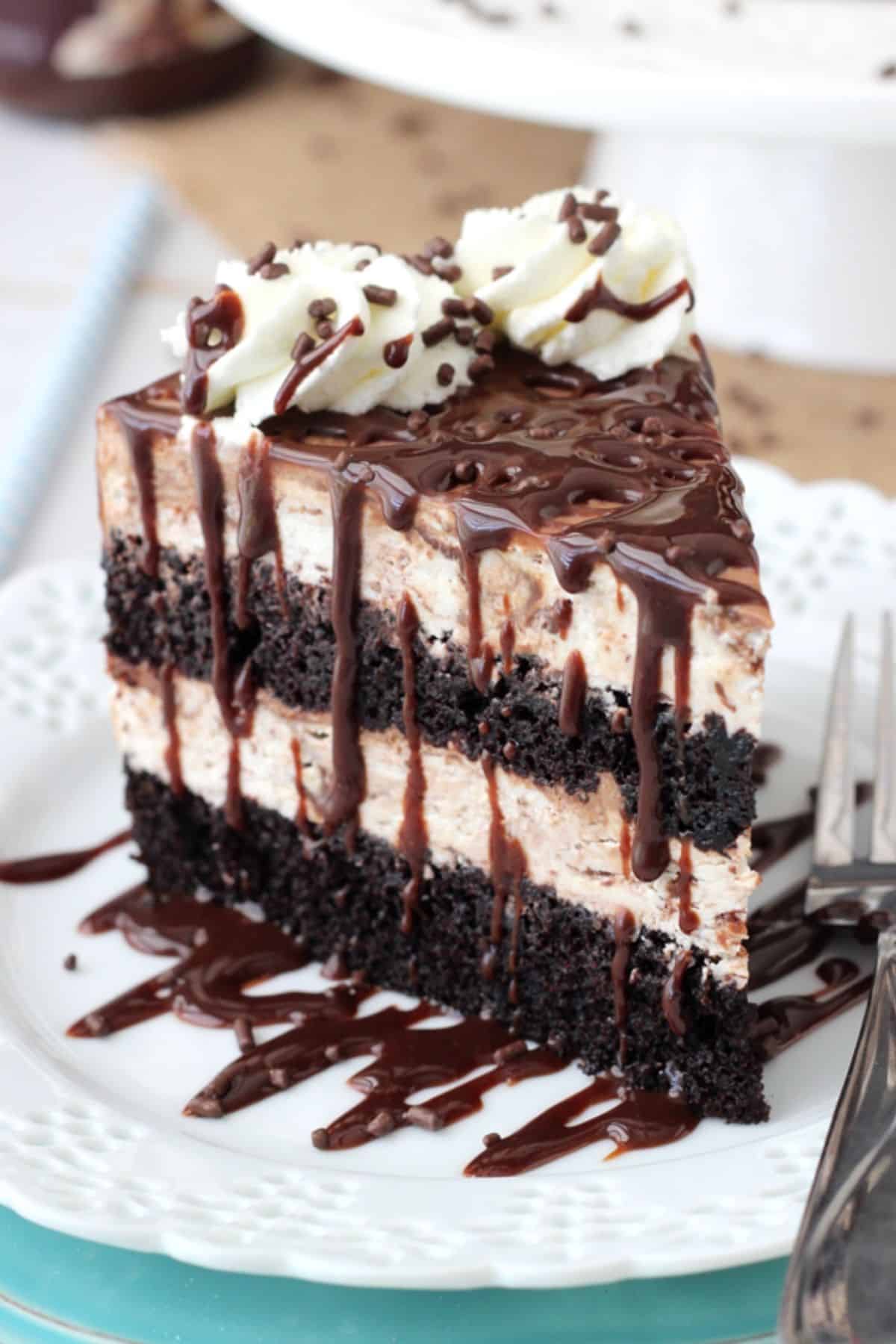 A tall slice of hot fudge swirl ice cream cake on a small white plate.