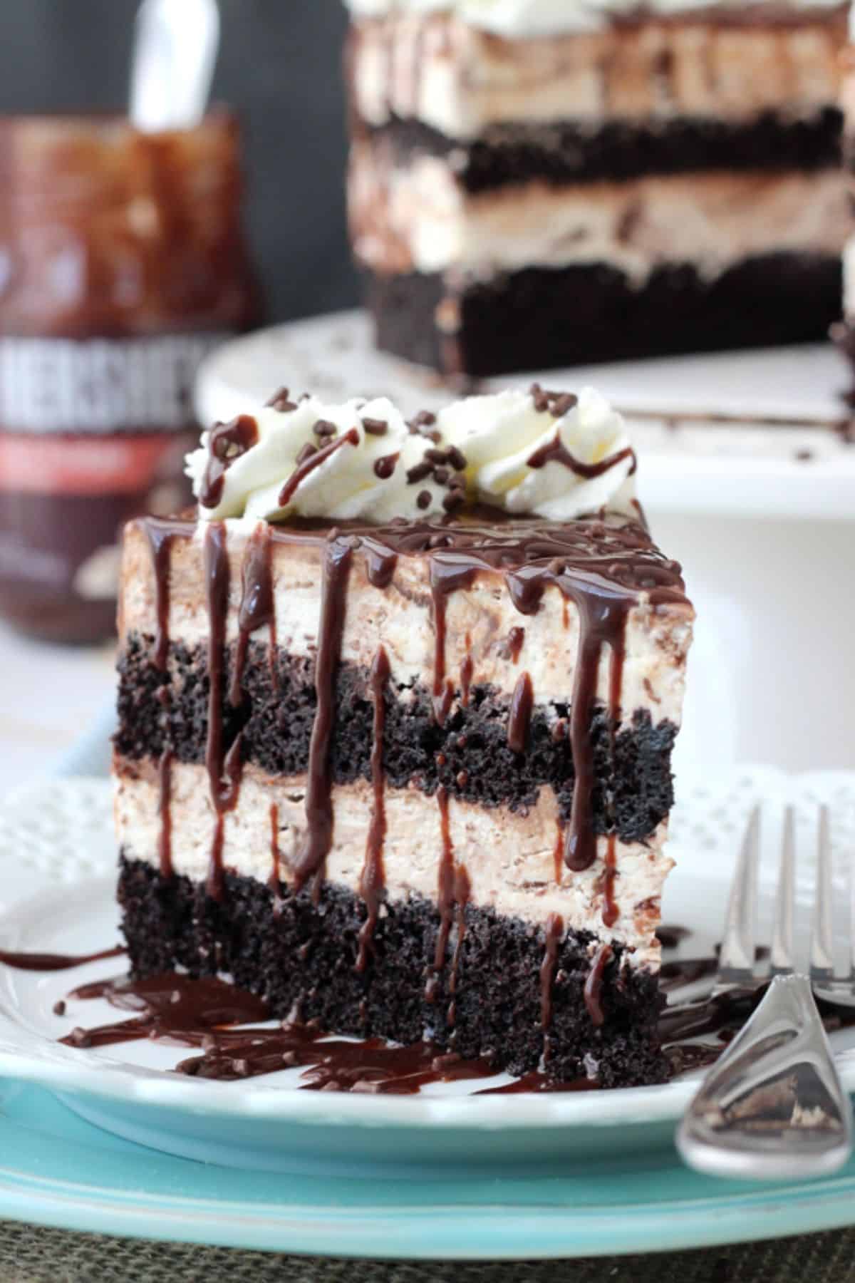 Close up of a slice of hot fudge swirl ice cream cake on a small white plate.