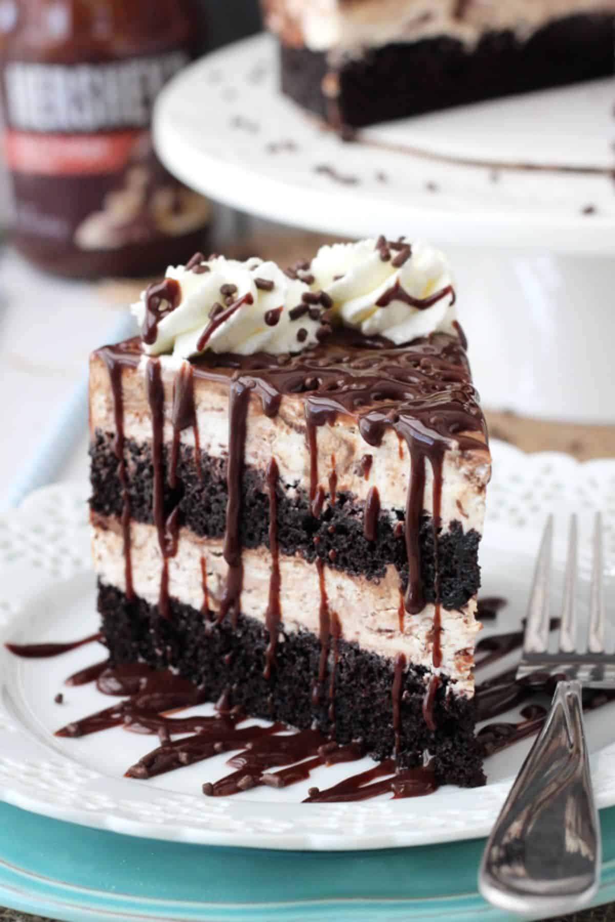 Close up of a slice of hot fudge swirl ice cream cake on a white plate.