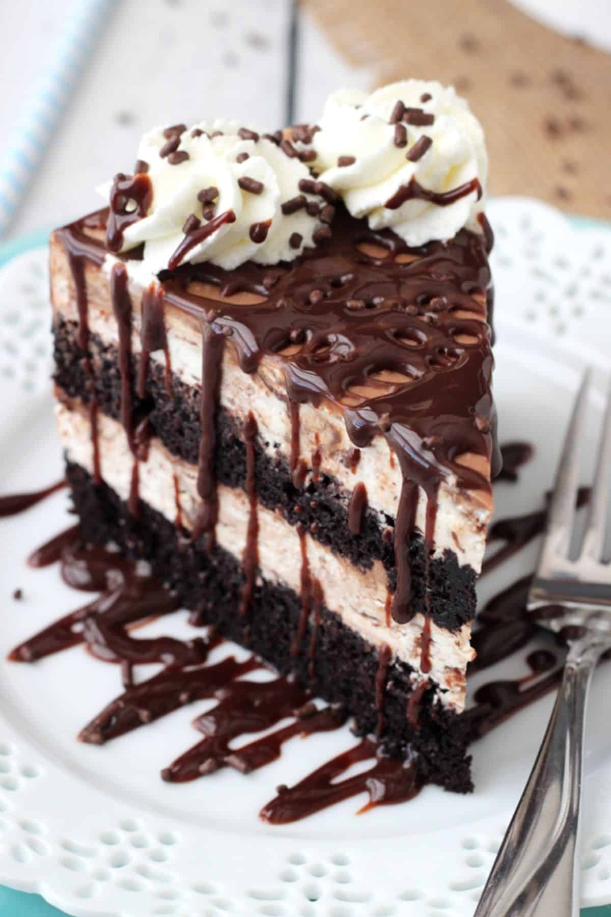 A slice of hot fudge swirl ice cream cake on a small white plate.
