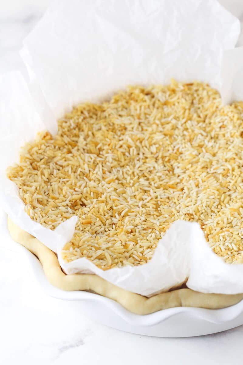 Parchment paper and rice on a pie crust to blind bake it
