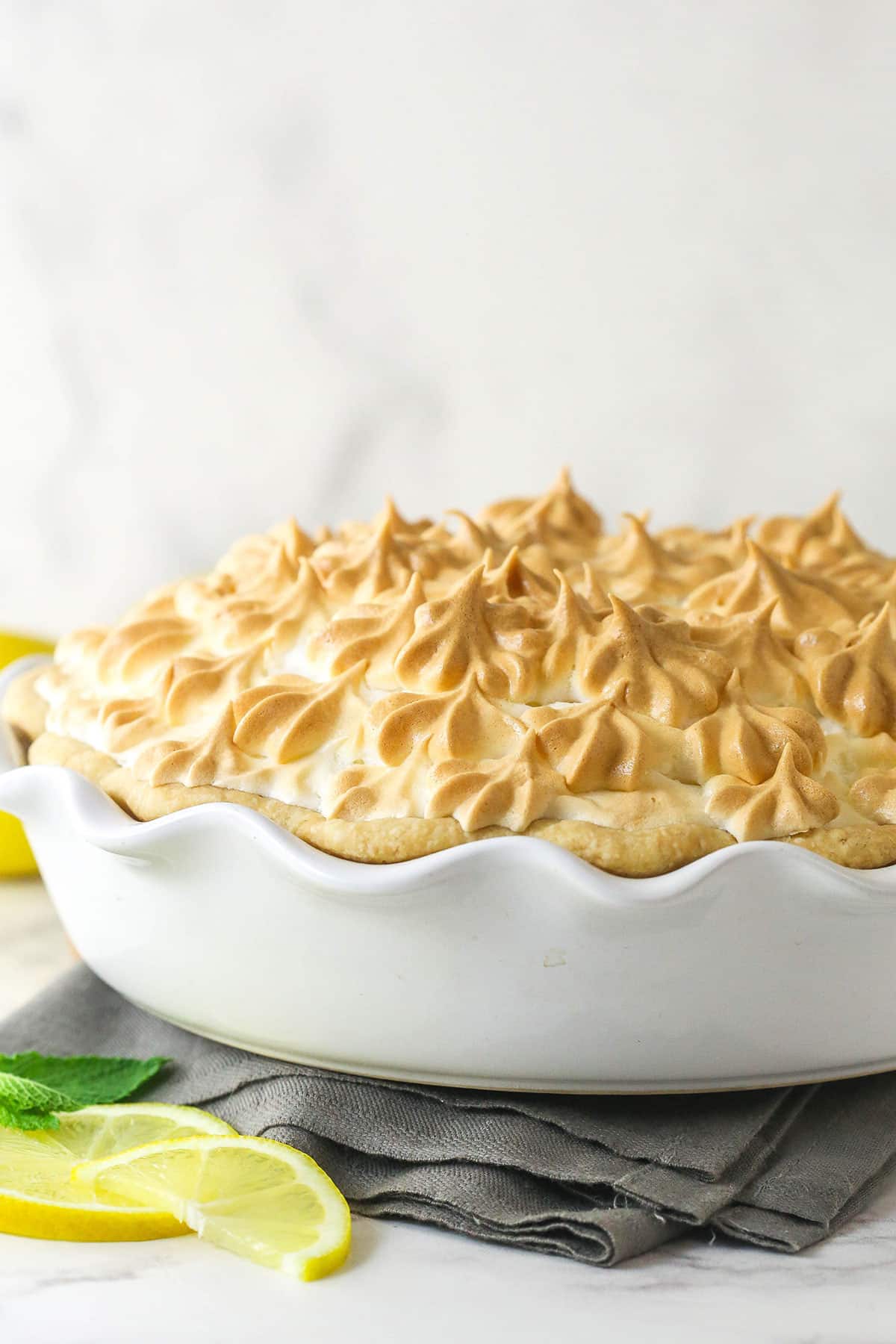 This classic lemon meringue pie features a tart lemon filling in a buttery crust topped with a light but stable meringue. Side view of a lemon meringue pie