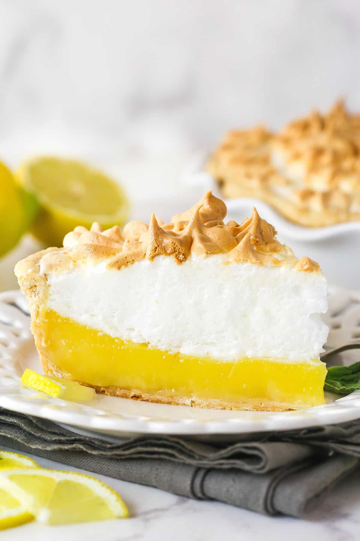 This classic lemon meringue pie features a tart lemon filling in a buttery crust topped with a light but stable meringue. Side view of a slice of lemon meringue pie on a plate