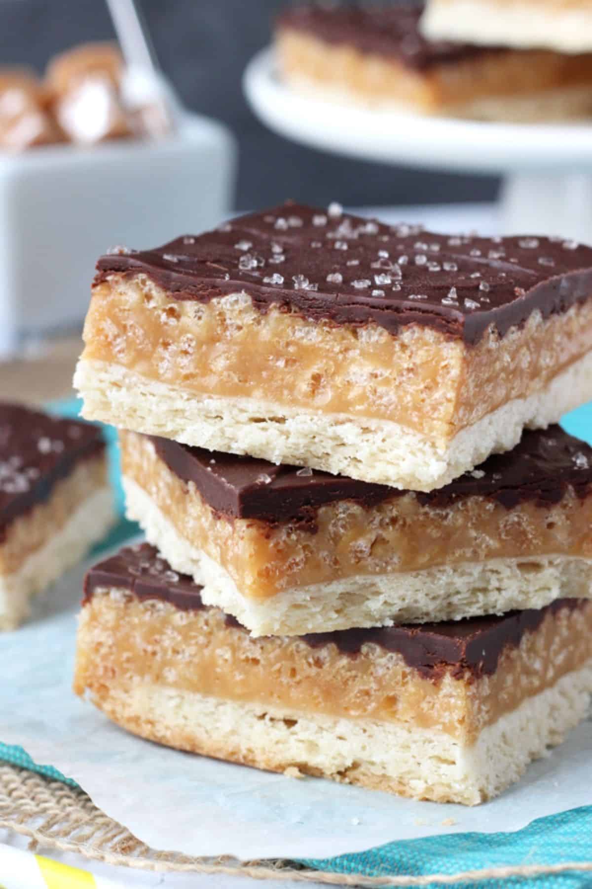 Close up of three caramel shortbread bars on a teal napkin.