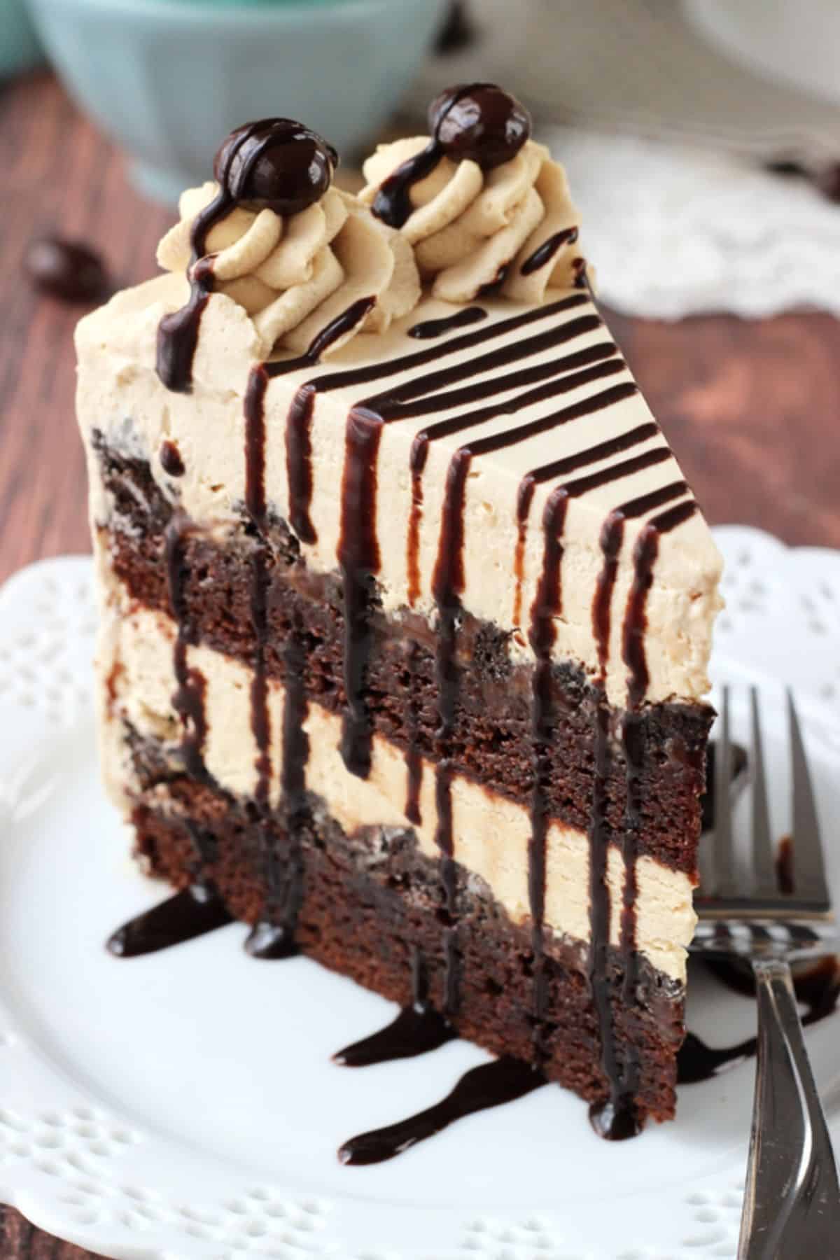 Close up of a tall slice of mocha brownie ice cream cake on a white plate.