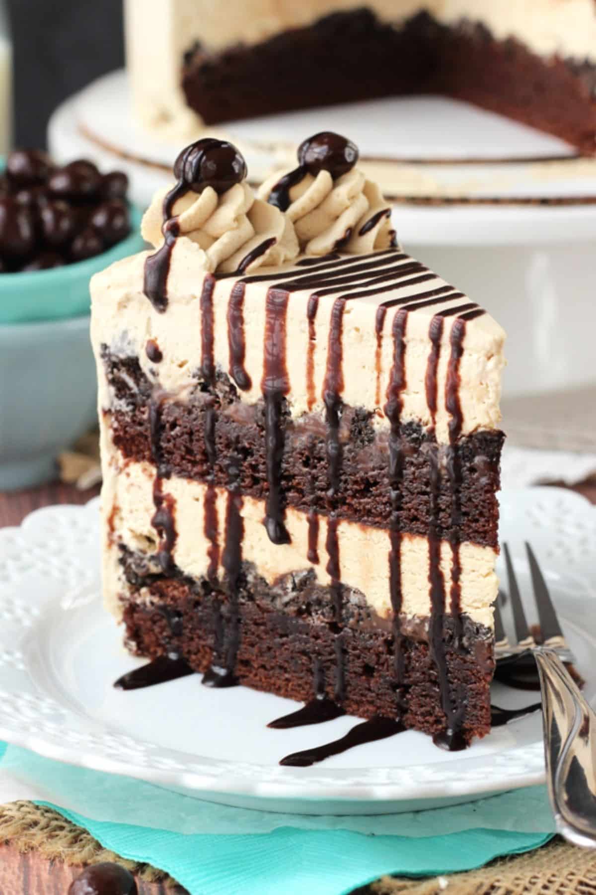 A slice of mocha brownie ice cream cake standing upright on a white plate.