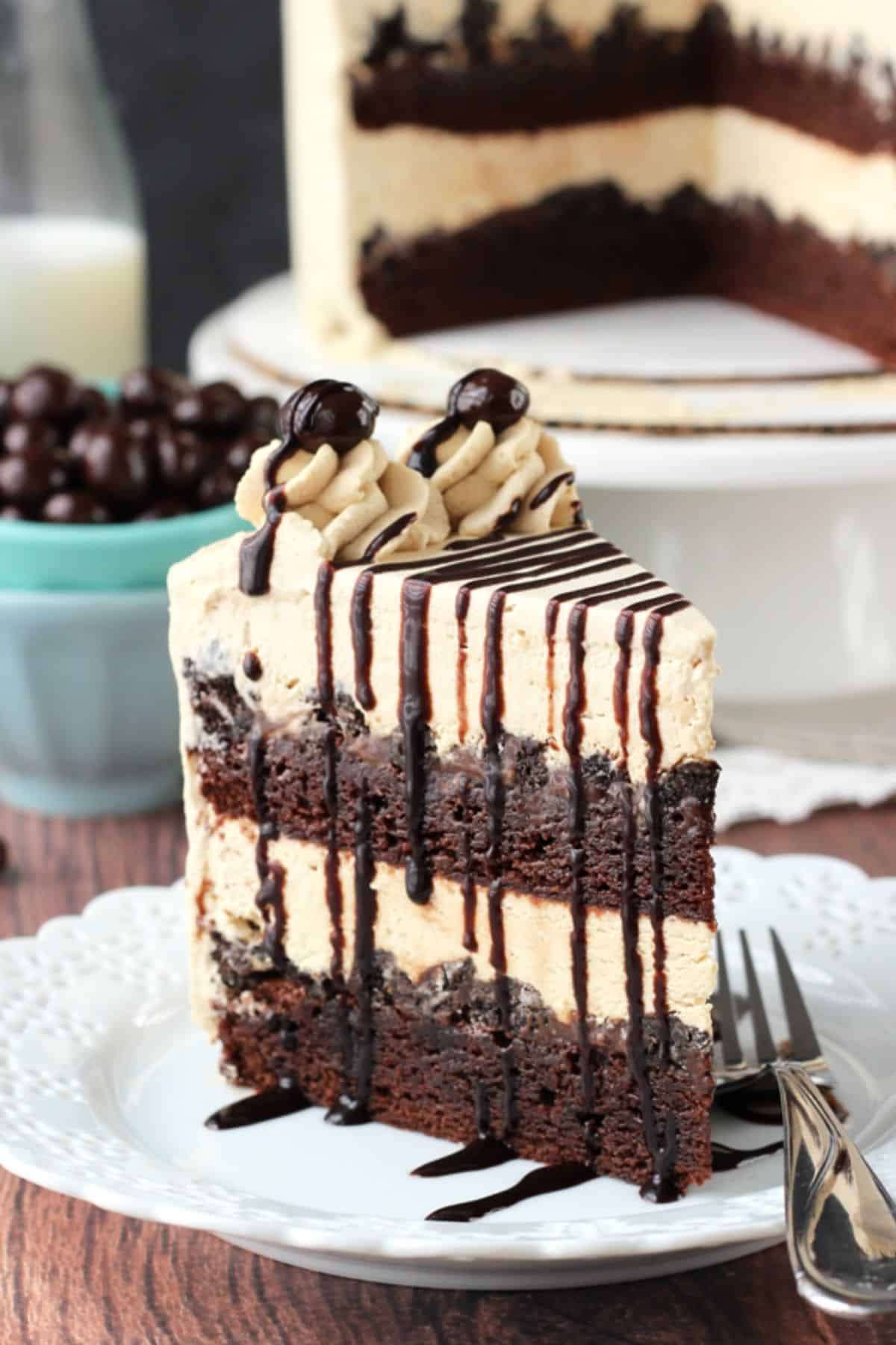 Close up of a slice of mocha brownie ice cream cake standing upright on a white plate.
