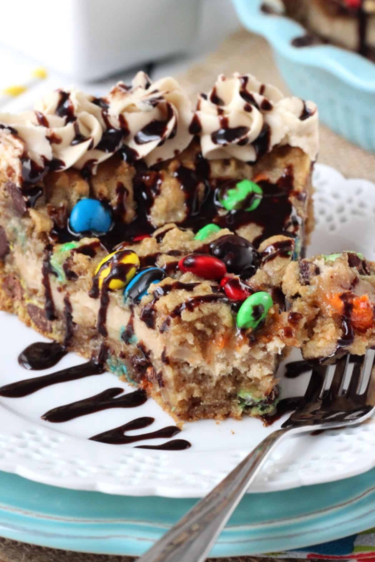 Close up of a slice of monster cookie cheesecake pie with a bite removed on a fork.