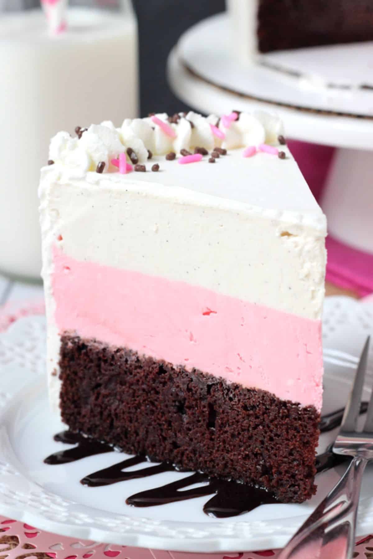 Side view of a slice of neapolitan ice cream cake on a small white plate.