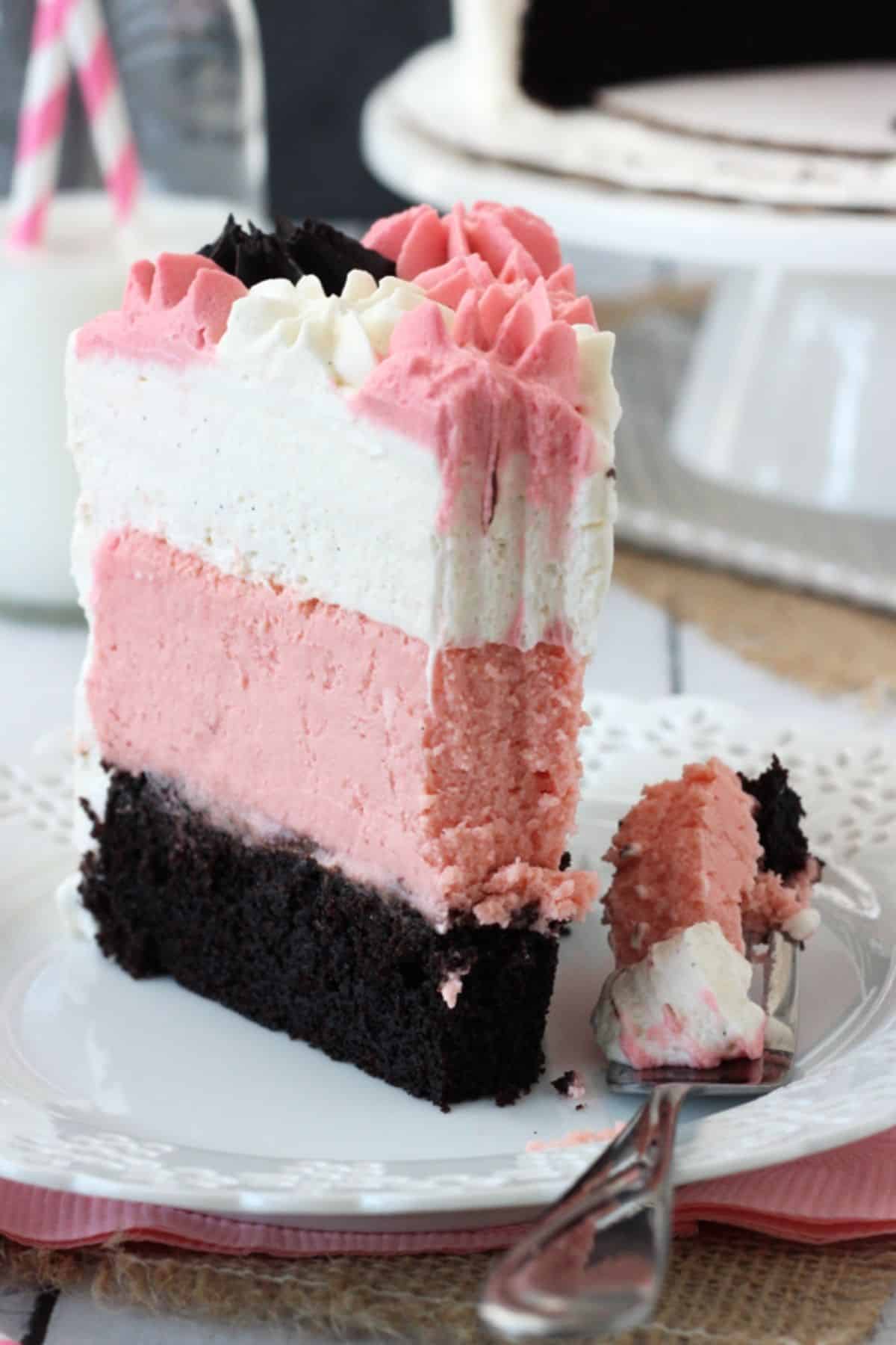 A slice of neapolitan millionaire cake with a bite removed on a fork.