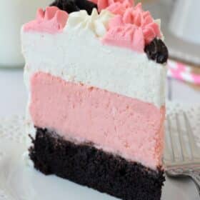 A tall slice of neapolitan millionaire cake on a white plate.
