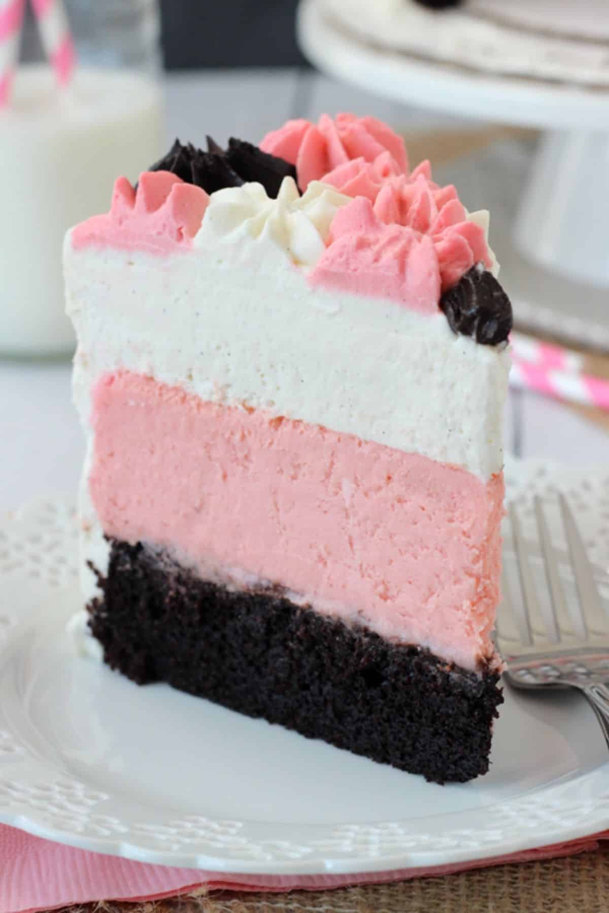 A tall slice of neapolitan millionaire cake on a white plate.