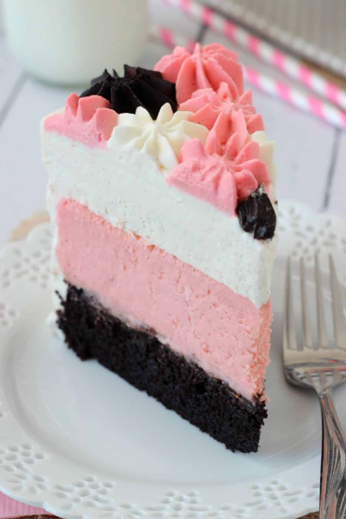 A tall slice of neapolitan millionaire cake on a white plate.
