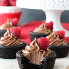 Close up of a Nutella cheesecake chocolate cookie cup with a bite taken out to show inside.