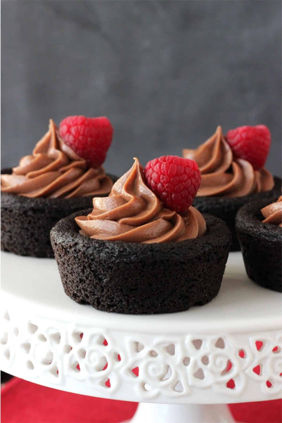 Close up of Nutella cheesecake chocolate cookie cups on a white cake stand.
