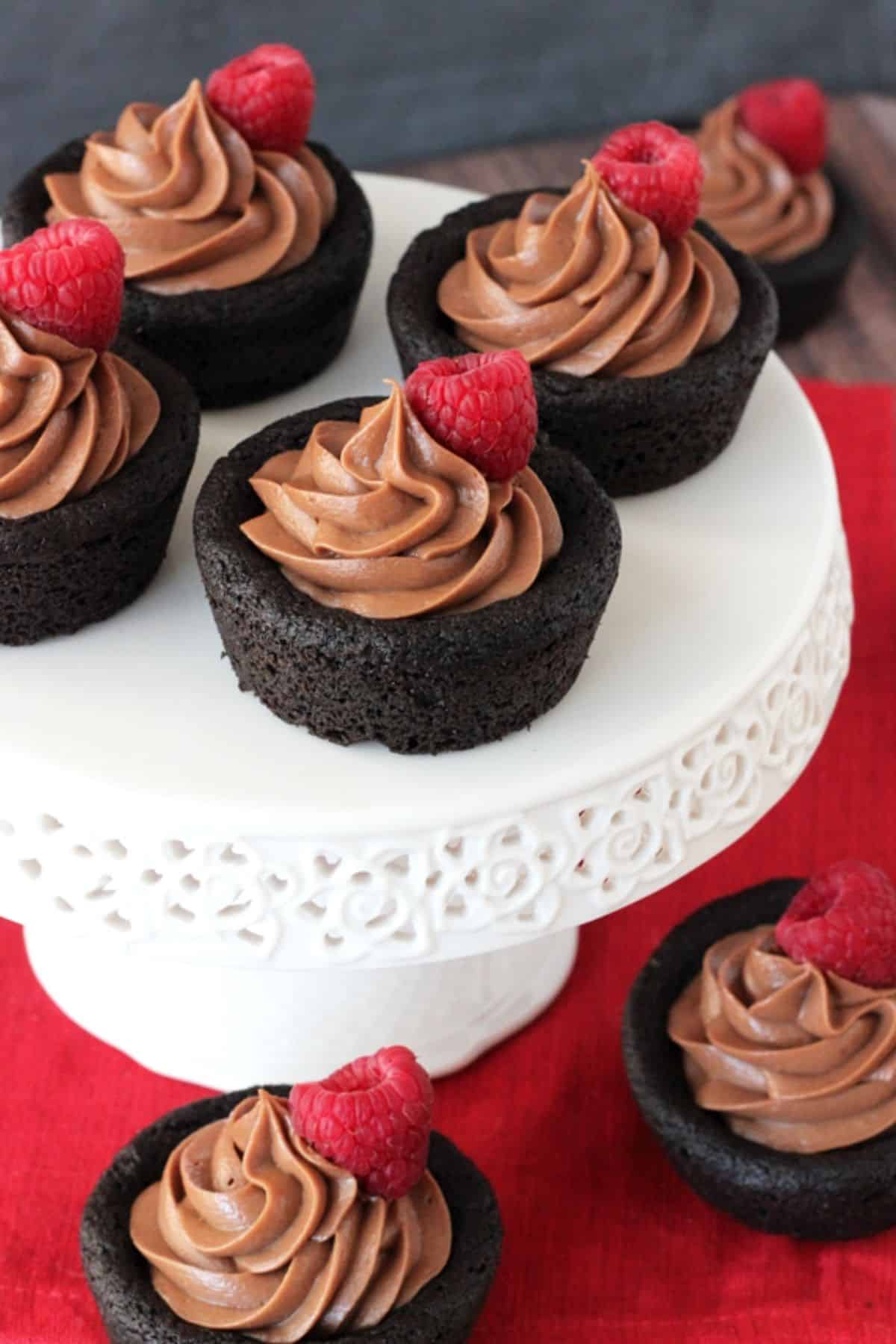 Nutella cheesecake chocolate cookie cups on a white cake stand with more cups below.