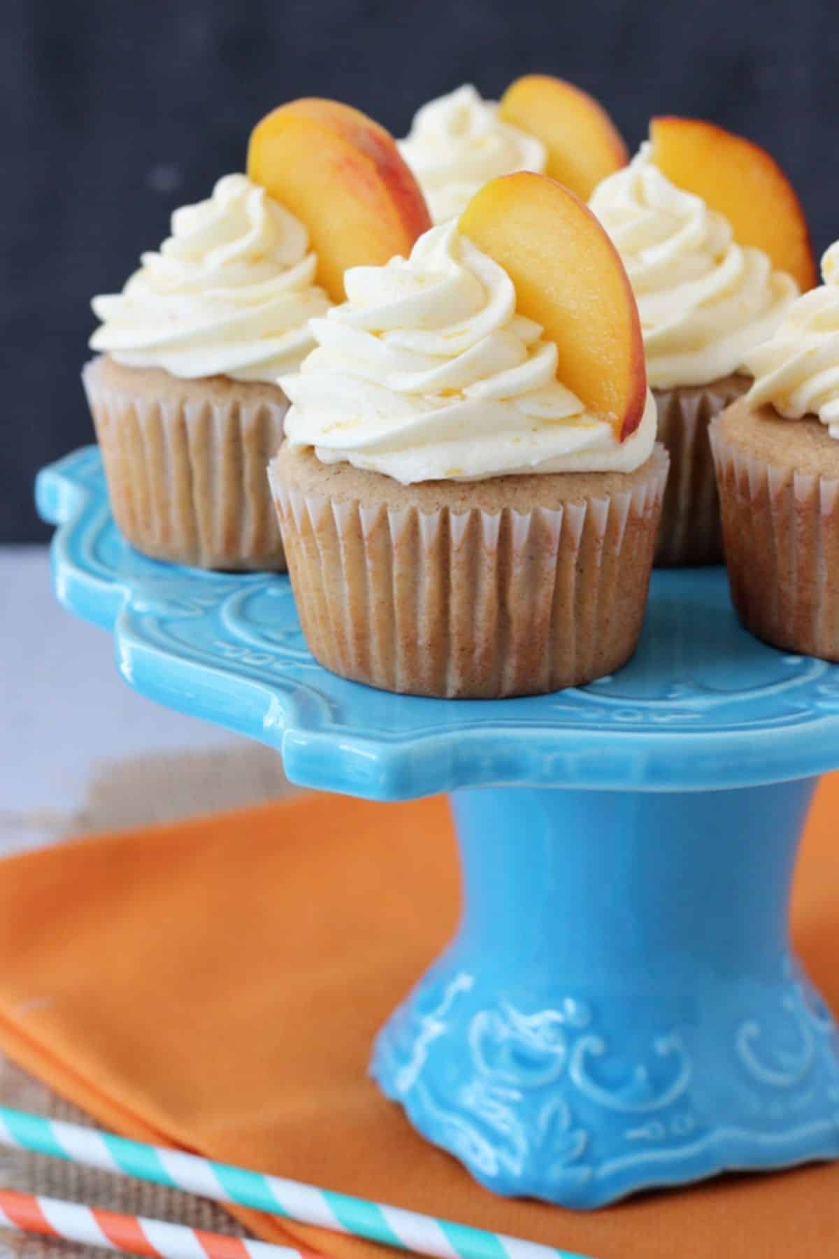 Several peach pie cupcakes on a blue cake stand.