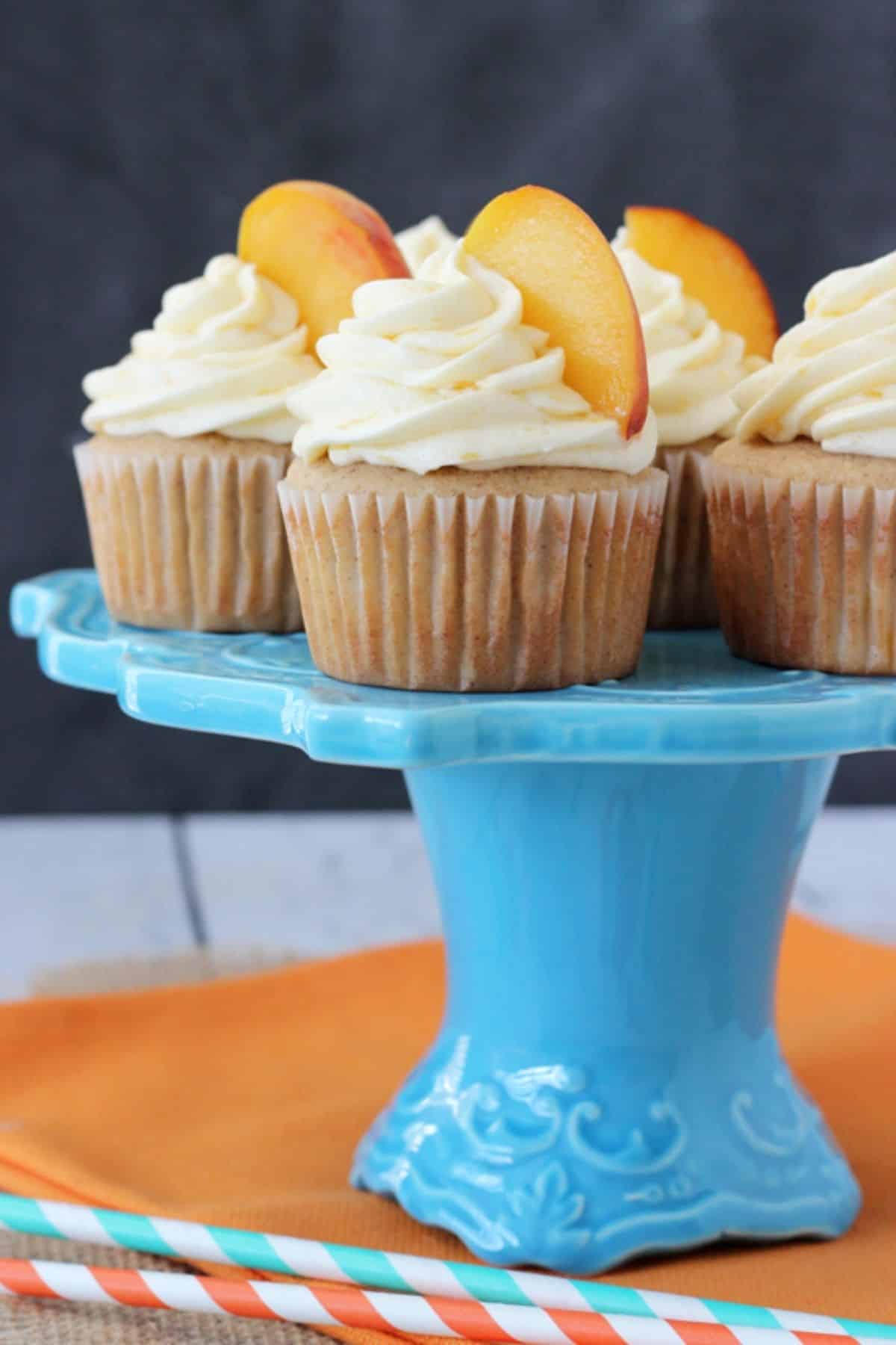 Several peach pie cupcakes on a blue cake stand.