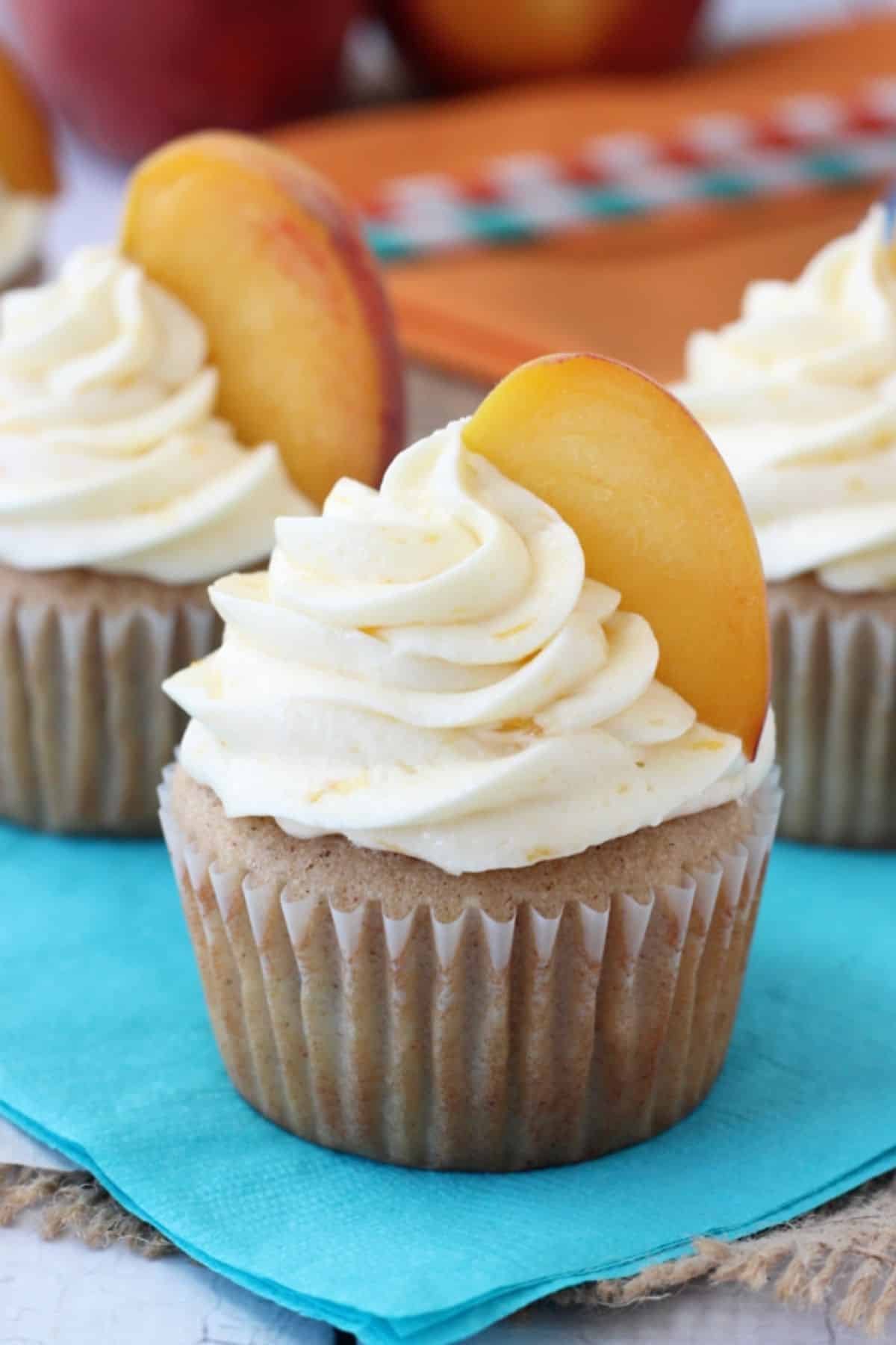 Close up of a peach pie cupcake on a teal napkin.